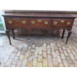 A Georgian oak three drawer dresser base with a shaped apron, some old repairs, replacement handles,