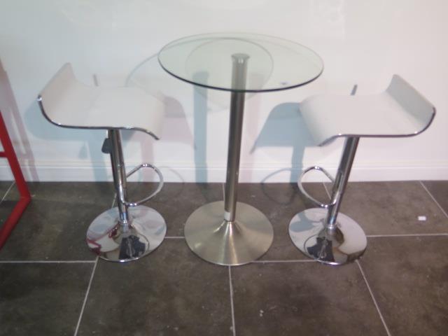 A glass top bar table, 91cm tall x 60cm diameter with two white laminated gas lift stools, some