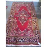 A hand knotted woollen rug with a red field, 280cm x 140cm, generally good condition