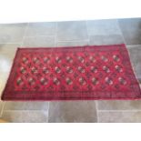 A small hand knotted woollen rug with a red field, 190cm x 96cm, generally good condition