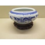 An oriental blue and white dragon bowl on a hardwood stand, total 14cm tall x 22cm diameter, no