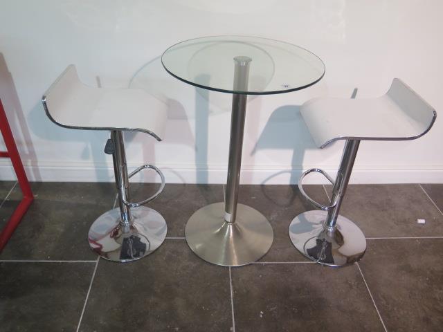 A glass top bar table, 91cm tall x 60cm diameter with two white laminated gas lift stools, some