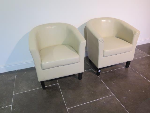 A pair of faux leather cream tub chairs, some usage marks but generally good