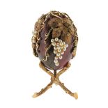 A gold-mounted hardstone egg, c1960, the rhodonite body mounted in a gold cagework of fruiting