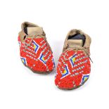 A pair of Plains moccasins hide with red, light and dark blue, white and yellow glass beads, with