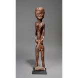 A Lobi standing female figure Burkina Faso with a plaited coiffure, 58cm high, on a base. (2)