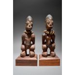 A pair of Yoruba Ibeji figures Nigeria male and female with inset metal pin pupils and with long