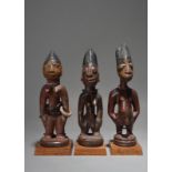 Three Yoruba Ibeji figures Nigeria including a male and two females, with beads, nut discs and an