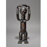 A Baule standing female figure Ivory Coast with a container on her head and wearing glass beads,