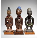 Three Yoruba Ibeji figures Nigeria including two males and a female, with beads and cowrie shells,