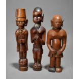 Three Kamba standing figures Kenya including an Askari, 26cm high and two females wearing skirts,