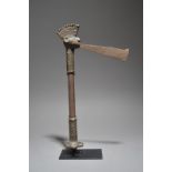 A Tiv anthropomorphic ceremonial axe Nigeria brass and iron, 46cm long, on a stand. (2) Provenance