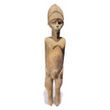 A Lobi standing male figure Burkina Faso with a cap and with his hands on the tops of his hips, 84cm