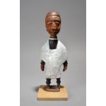 Thomas Ona A Yoruba carved figure of a priest standing wearing a dog collar and cassock, with