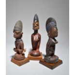 Three Yoruba Ibeji female figures Nigeria two with beads or cowrie shells, 22.5cm, 25cm and 27.3cm