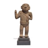 A Costa Rica standing figure volcanic rock, with a crossed and ribbed coiffure, holding an axe in