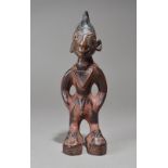 A Yoruba Ibeji male figure Nigeria with an Islamic tirah amulet and sandals, 25.7cm high.