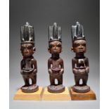 A set of Yoruba Ibeji triplets Nigeria two males and a female with quadripartite coiffure, eyelashes