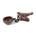 A Shona headrest Zimbabwe the support carved as a lying figure with a linked chain and a bowl,