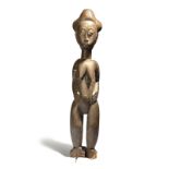 A Baule style standing female figure Gold Coast with a lobed coiffure and with her hands to the