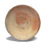 A shallow dish probably Cypriot terracotta decorated with square, circle and wavy line central