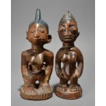 Two Yoruba Ibeji female figures Nigeria both with crested coiffures and one with nut shell beads,