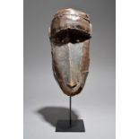 A Makonde monkey mask Mozambique/Tanzania with nailed leather, 29.5cm high, on a stand. (2)