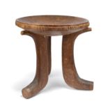 A Jimma stool Ethiopia with a carved edge to the dipped seat and on three scroll legs, 40.5cm