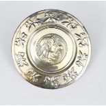 An electroplated metal charger, the well decorated with a portrait of a young male classical