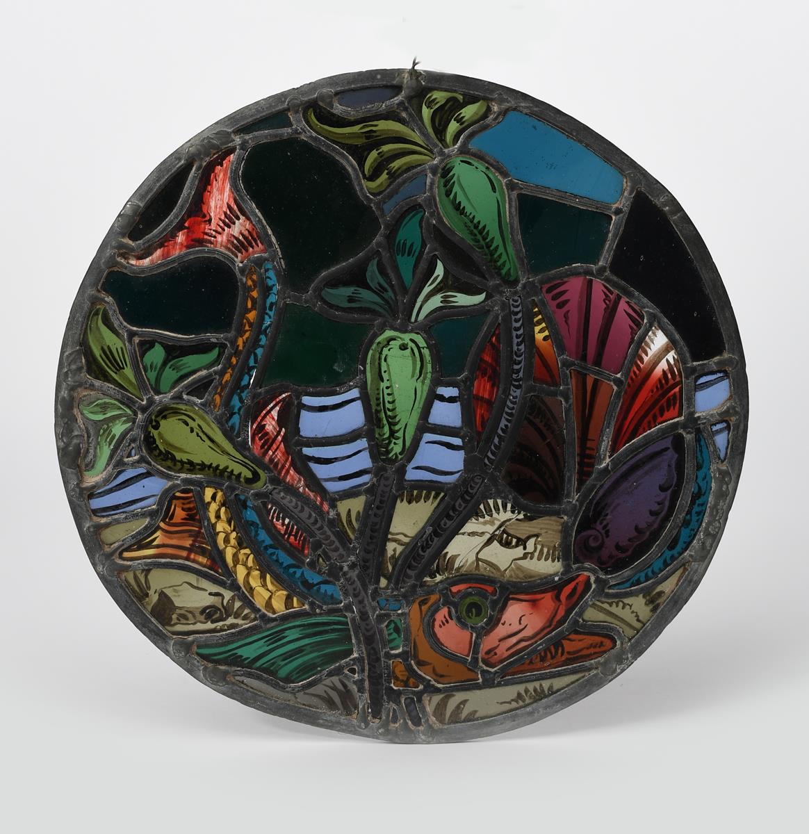 An Arts and Crafts stained glass roundel, decorated with a pike swimming amongst water lily flowers,