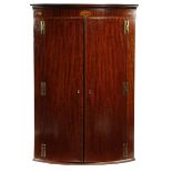 A GEORGE III MAHOGANY BOWFRONT HANGING CORNER CUPBOARD LATE 18TH CENTURY the frieze inlaid with