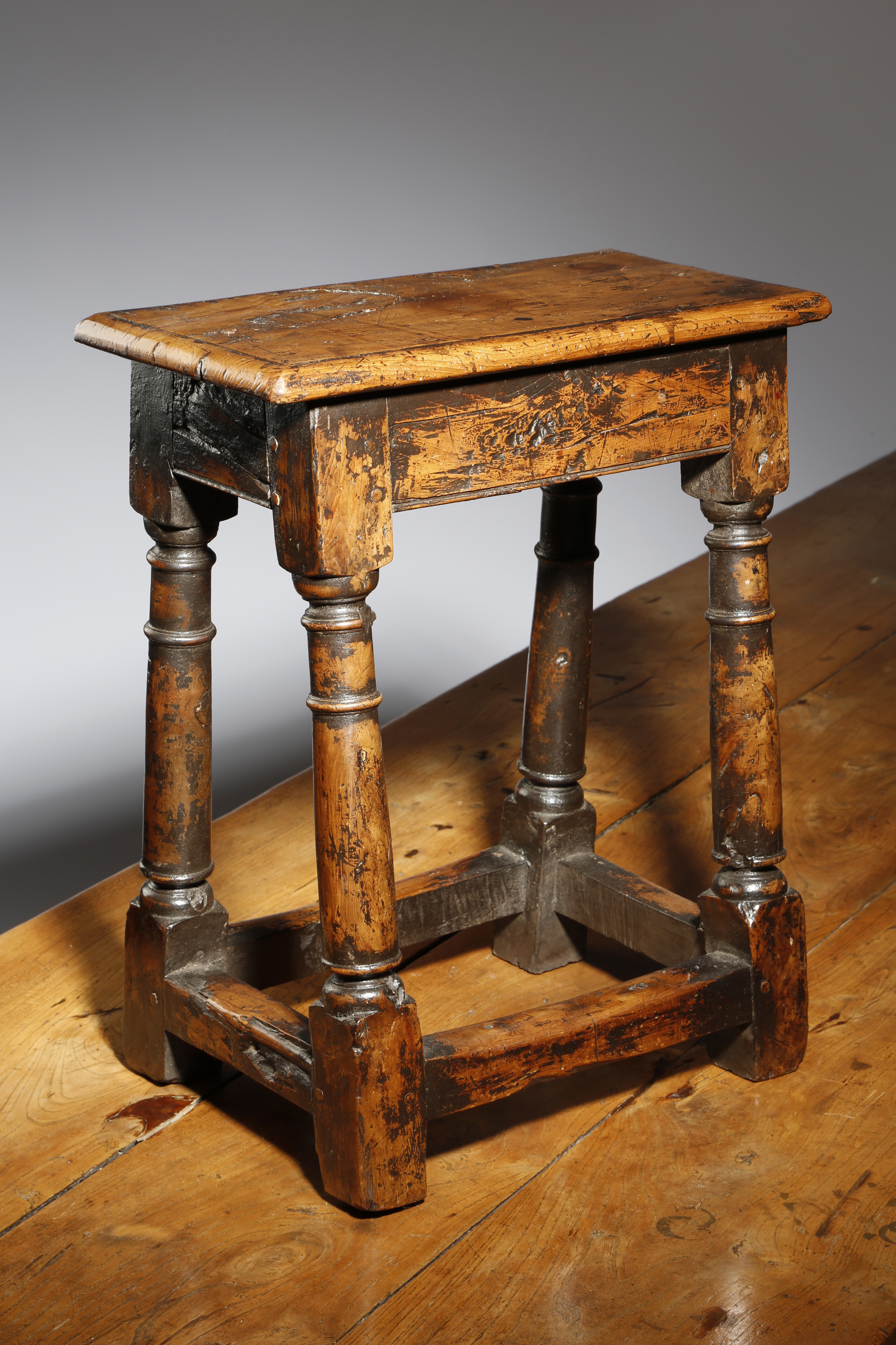 A YEW JOINT STOOL WITH 17TH CENTURY ELEMENTS the seat with a moulded edge above a plain frieze, on