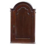 A GEORGE II OAK HANGING CORNER CUPBOARD the arched top above a shaped fielded panel door,