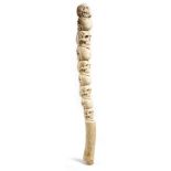 A FOSSILISED WALRUS OOSIK BONE carved with nine human skulls and with a handgrip 49cm long