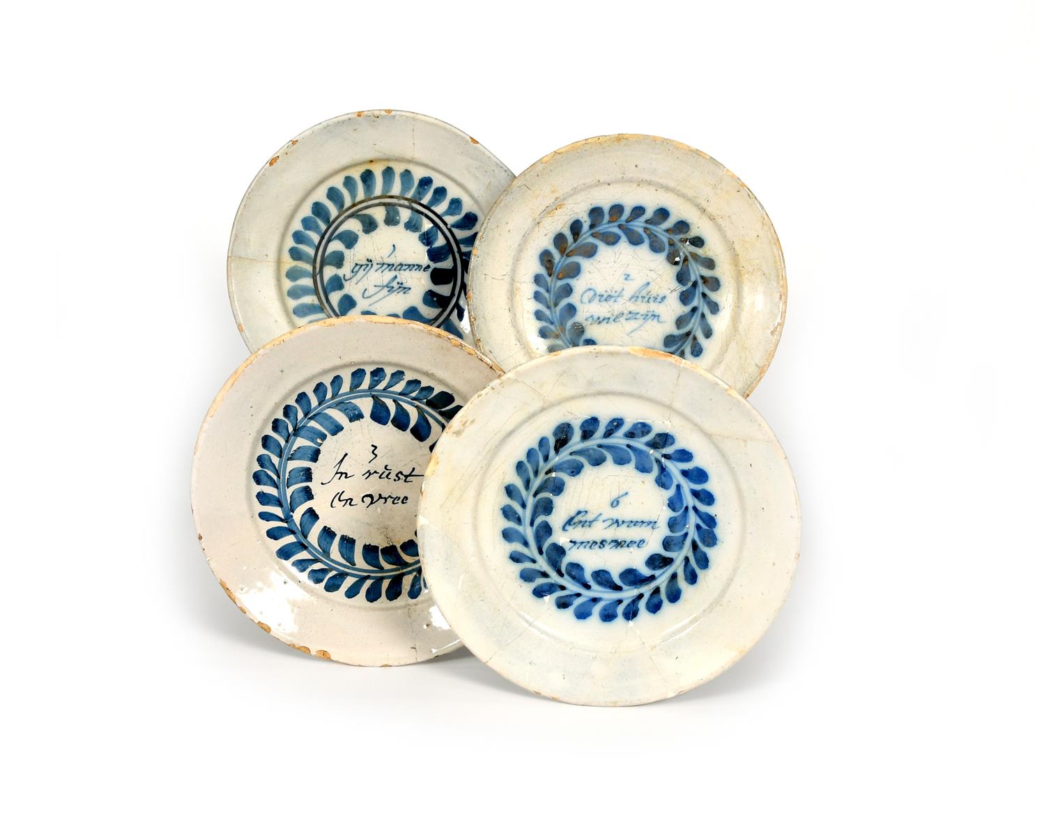 Four Delft 'Merry Man' plates, late 17th century, each well inscribed in Dutch with a line from