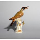 A Meissen model of a green woodpecker, 19th century, perched on a tree stump with head turned to