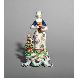 A Bow figure of a young girl, c.1760-65, standing and holding a bird's nest containing two chicks, a