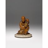 A CHINESE SOAPSTONE SEATED FIGURE QING DYNASTY OR LATER Carved as a luohan holding a small lion
