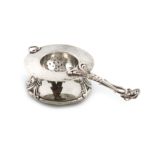 By G. A. Dahlgren, a Swedish silver tea strainer and stand, Malmo 1906, circular form, spot-hammered