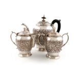 A three-piece Indian metalware tea set, unmarked hinged covers, baluster form, chased foliate scroll