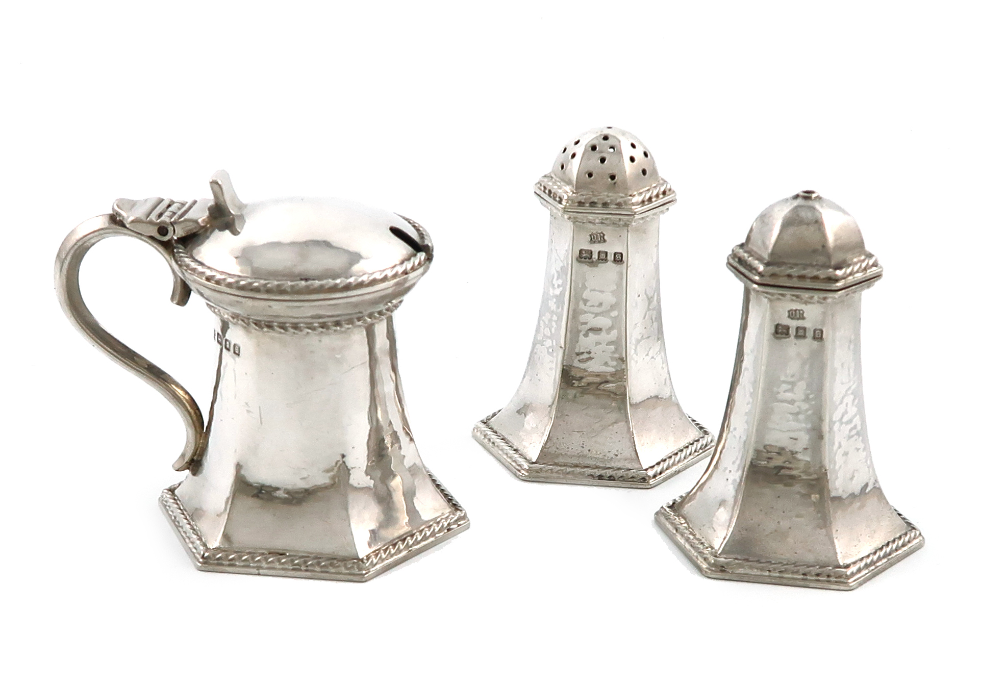 By Omar Ramsden, a three-piece Arts and Crafts silver condiment set, London 1933, the salt and