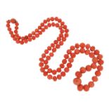 λ A single-row coral bead neckace, the beads graduate from 9 - 19mm, 90cm long Accompanied by