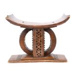 An Ashanti stool Ghana with a carved and pierced support, 43cm high, 53cm long.