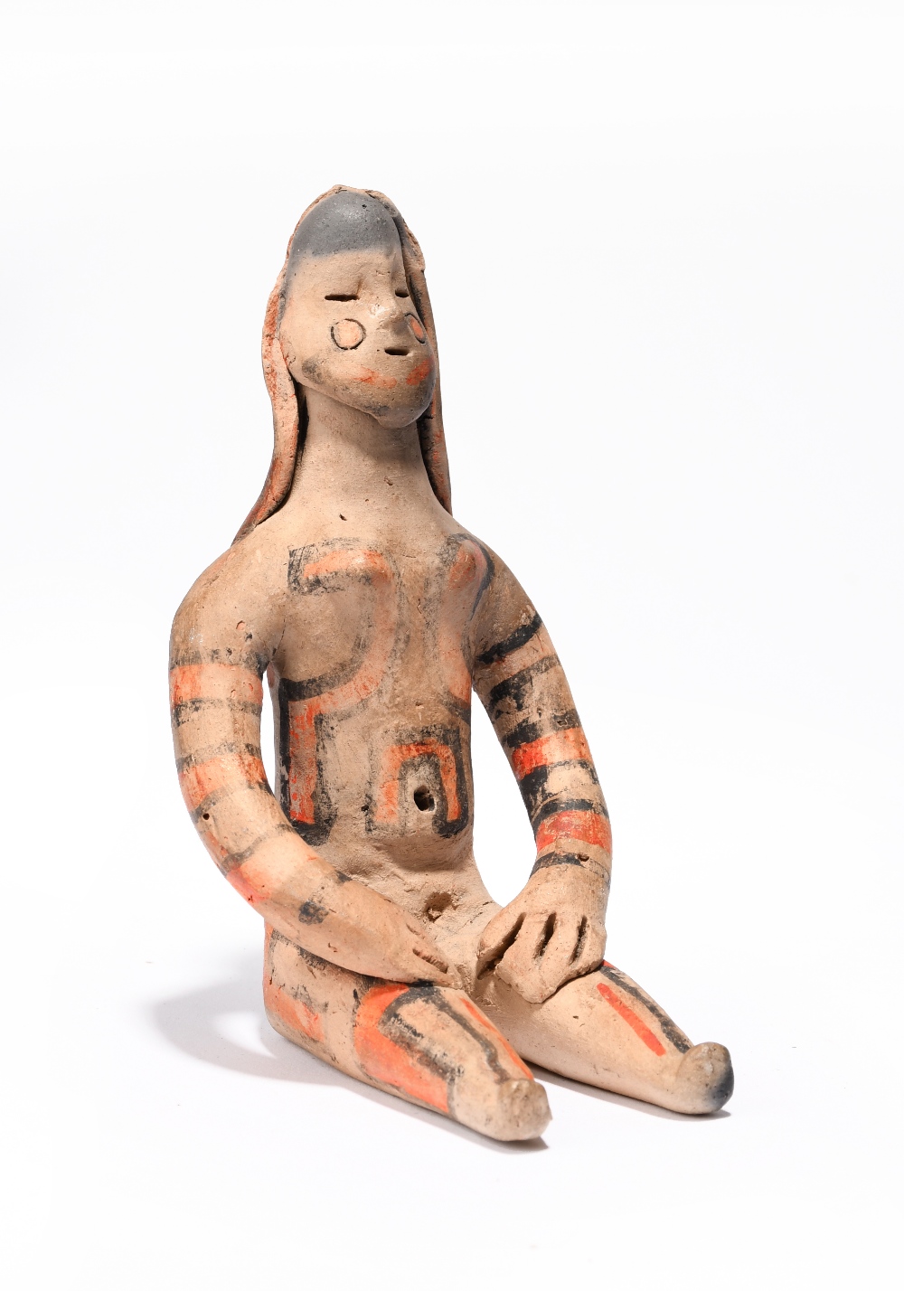 An Amazonian seated female figure Brazil earthenware with red and black decoration, 12cm high.