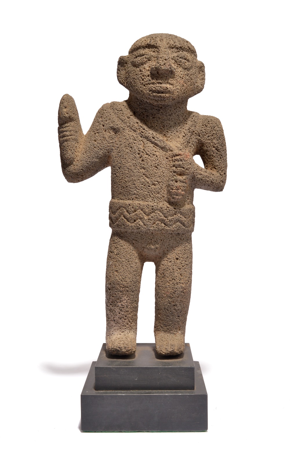 A Costa Rica standing figure volcanic rock, with a crossed and ribbed coiffure, holding an axe in