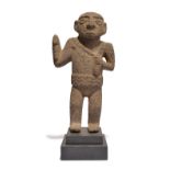 A Costa Rica standing figure volcanic rock, with a crossed and ribbed coiffure, holding an axe in