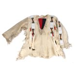 A Blackfoot shirt Plains tanned buckskin with fringes and with applied beaded panels having