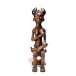 A Fante maternity figure Ghana seated on a stool with an infant on her lap, with ebonised highlights