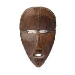 A Dan mask Ivory Coast with aluminium strips to the eyes, 22.5cm high. Provenance Donald Tait
