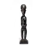 A Baule standing female figure Ivory Coast with facial and body scarifications, 48cm high, on a